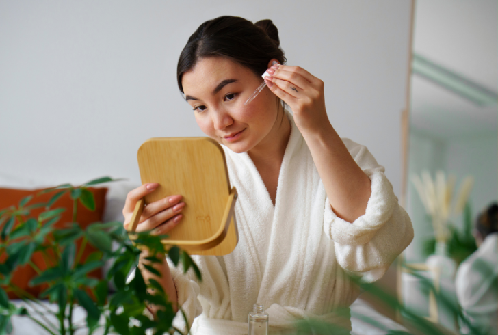 Woman applying serum with mirror