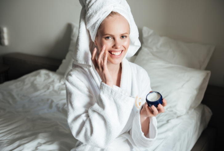Woman applying thick night cream moisturizer