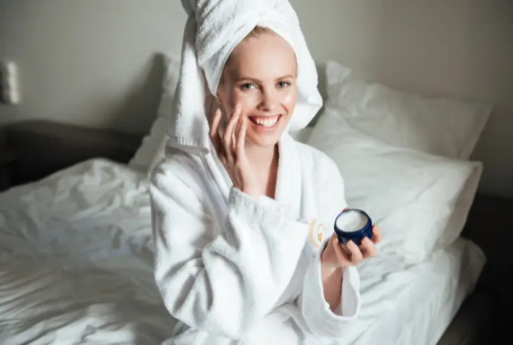 Woman applying thick night cream moisturizer